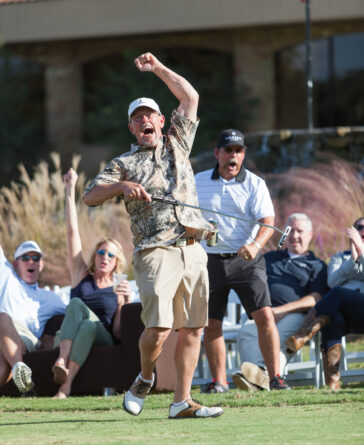 man swinging golf club with crowd watching