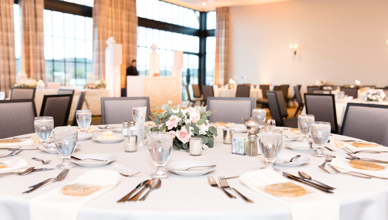 wedding reception table with elegant place settings and flowers