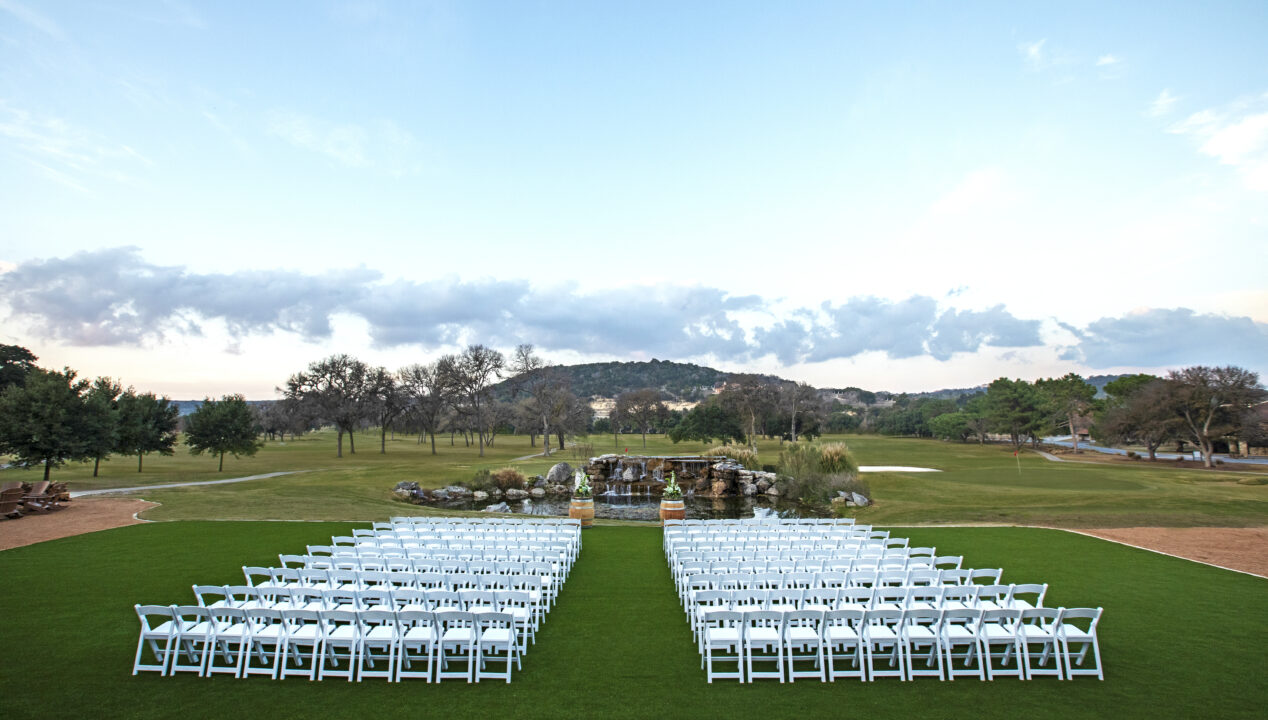 outdoor wedding ceremony setup with rows of white chairs on lawn