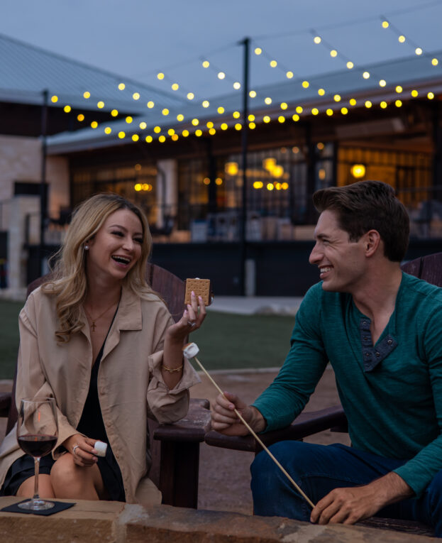man and woman smiling with s'mores outdoors
