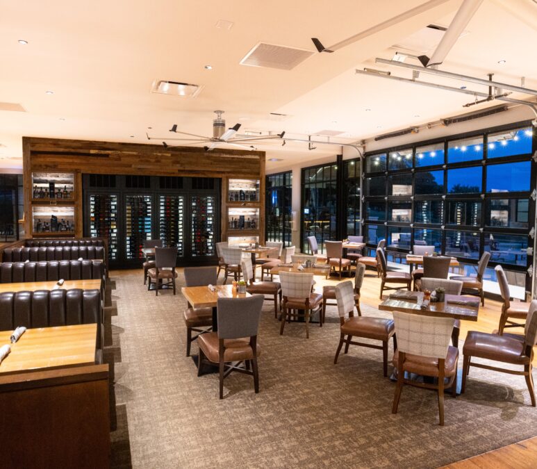 A dimly lit restaurant dining room with tables and chairs.