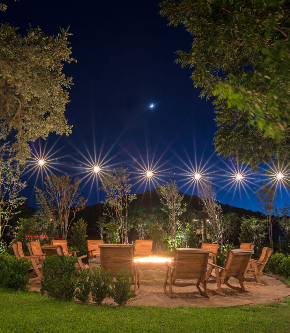 outdoor fire pit with chairs and string lights at night