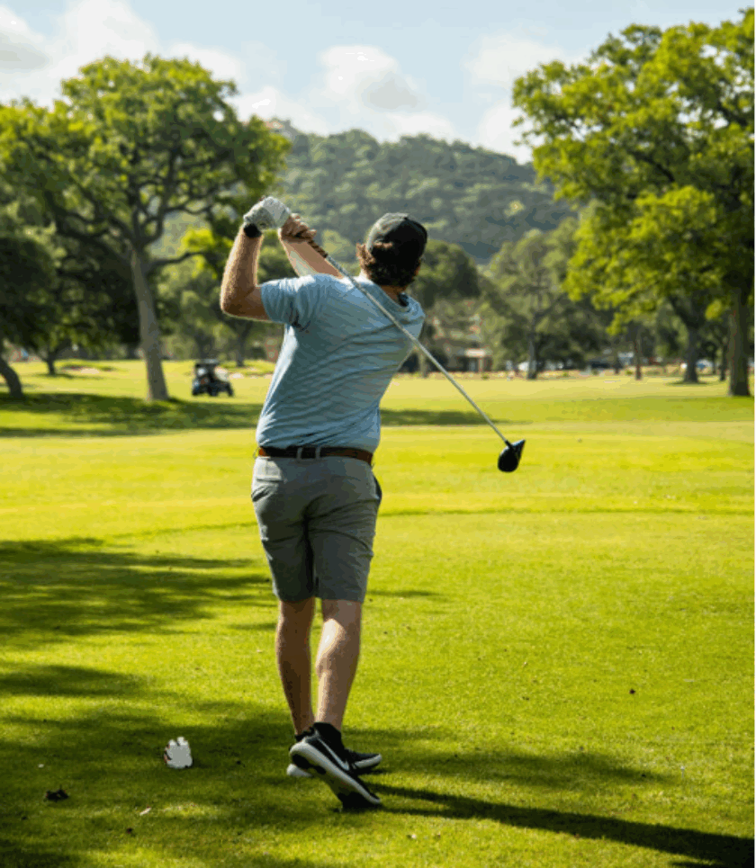 man swinging golf club on course