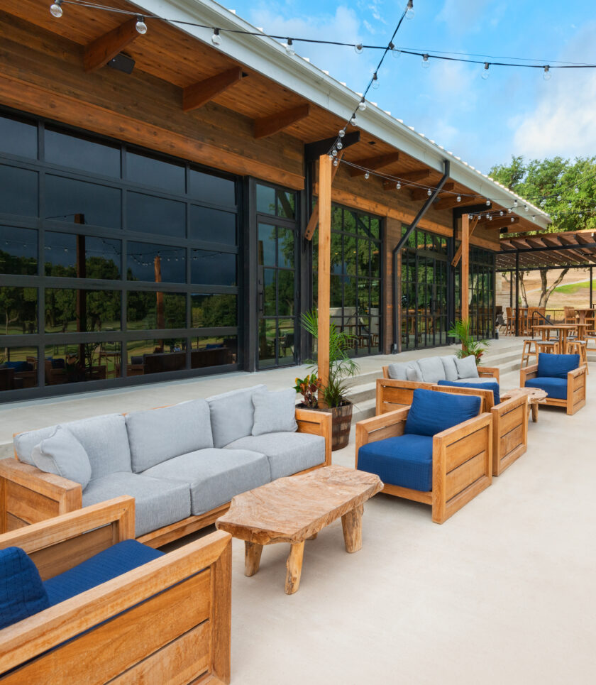 outdoor patio with wooden lounge chairs, sofas, and string lights