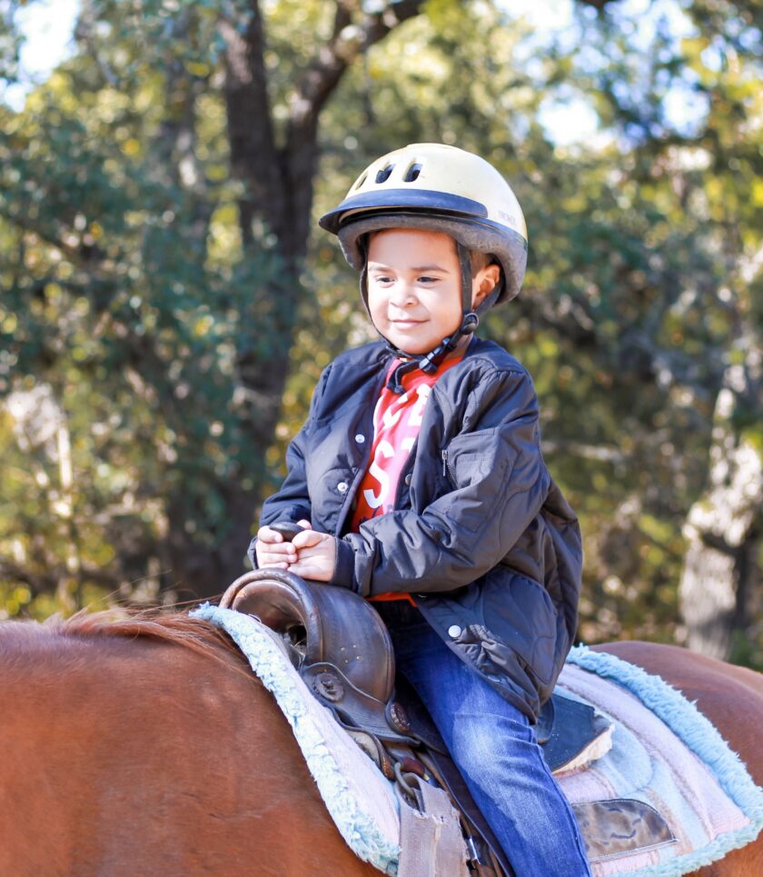 child wearing helmet riding a horse