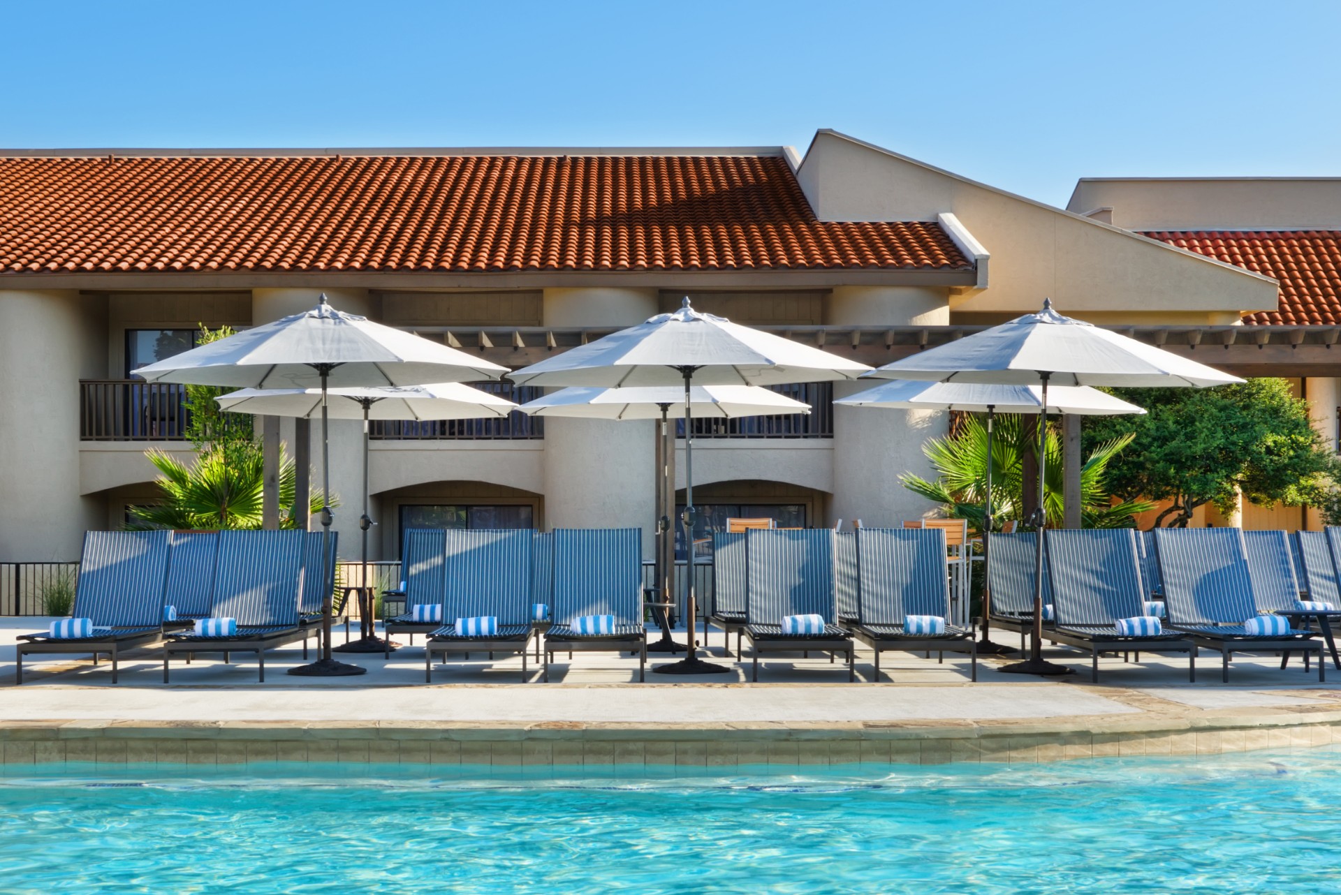 outdoor pool with lounge chairs and umbrellas