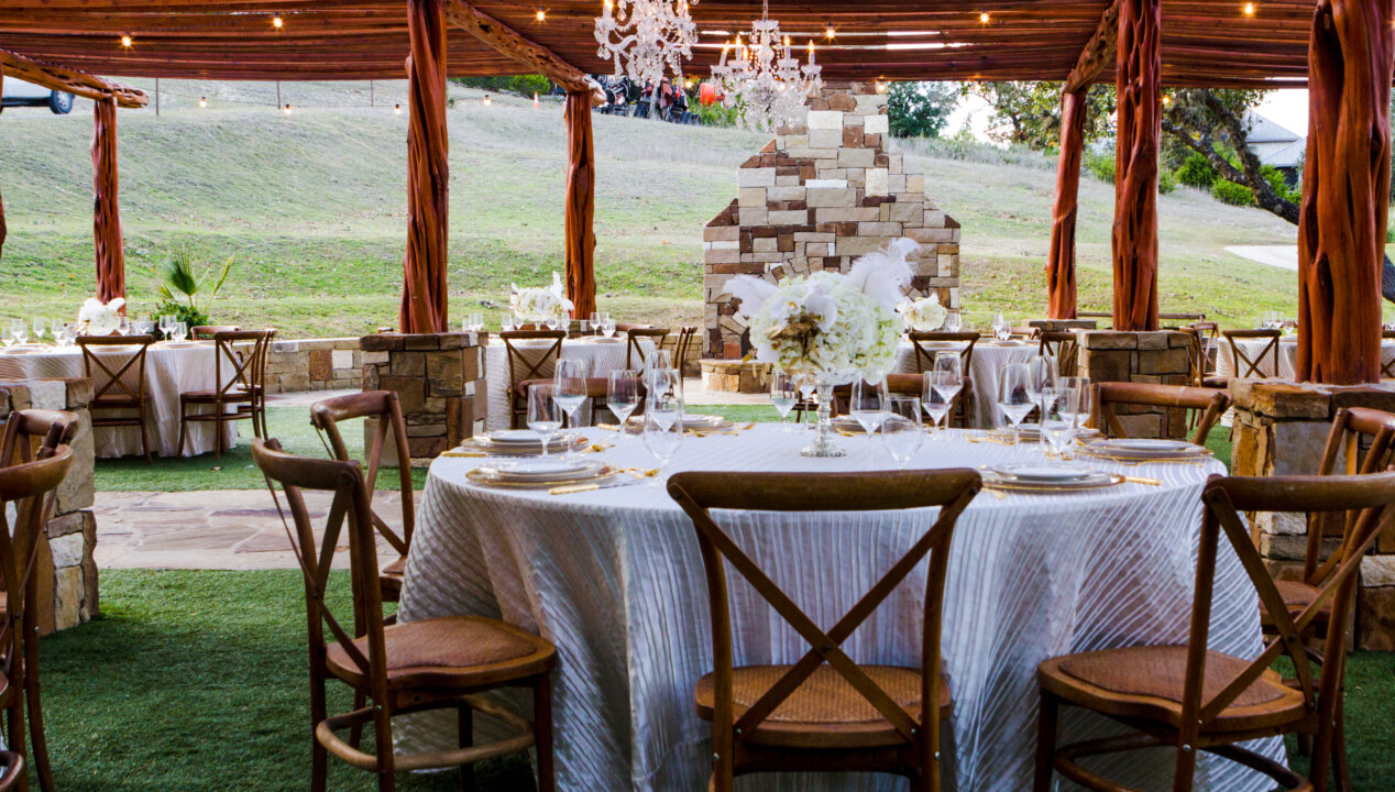 outdoor wedding reception table with chandelier and wooden chairs