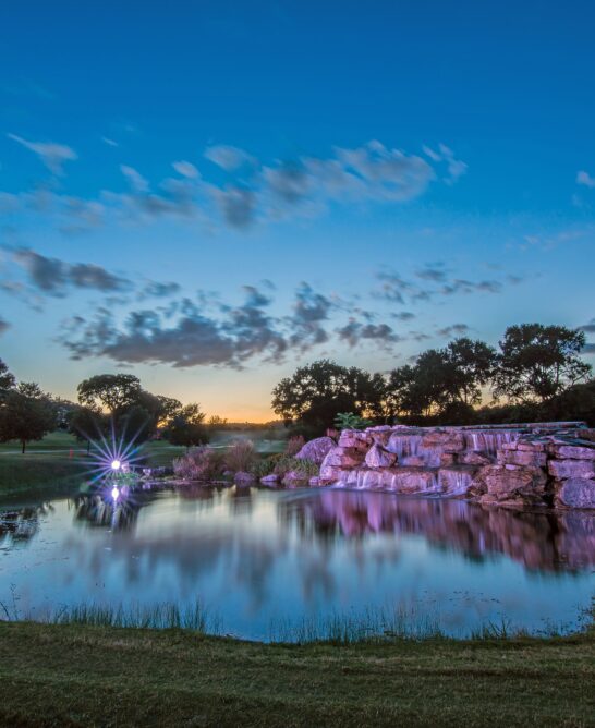 pond with rocks and trees at sunset