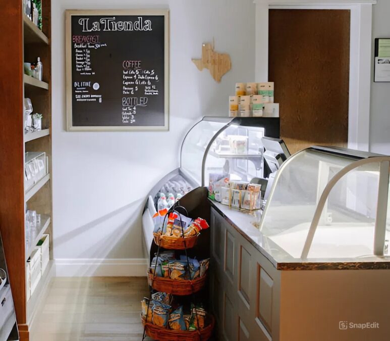 A small shop with a chalkboard menu and a glass display case. There are baskets of snacks on the floor.