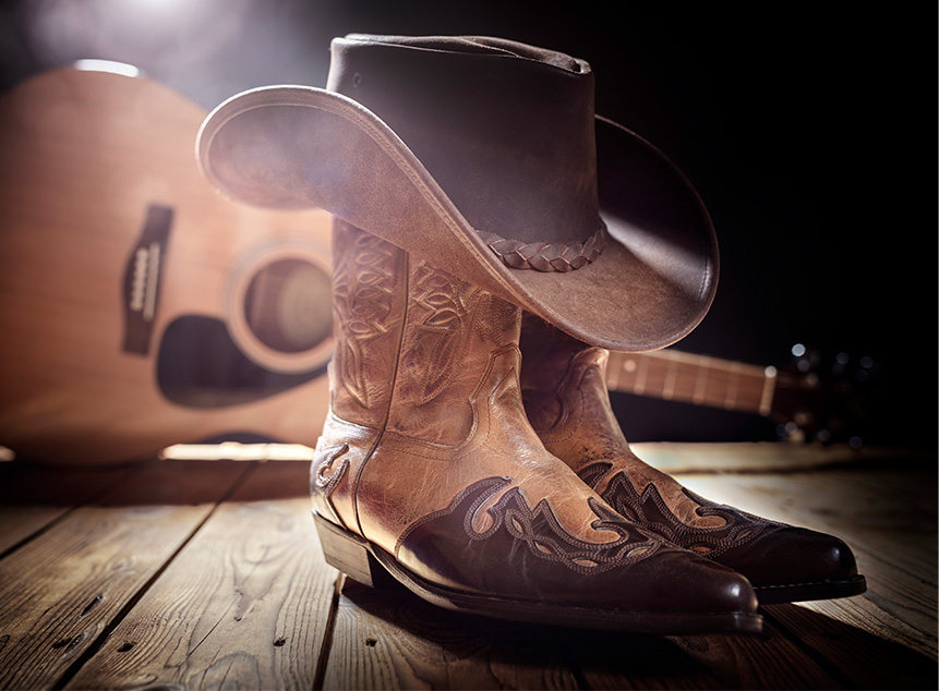 cowboy hat and boots next to acoustic guitar