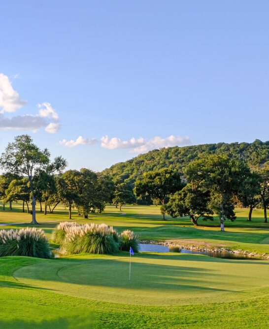 View of golf course with trees and hills