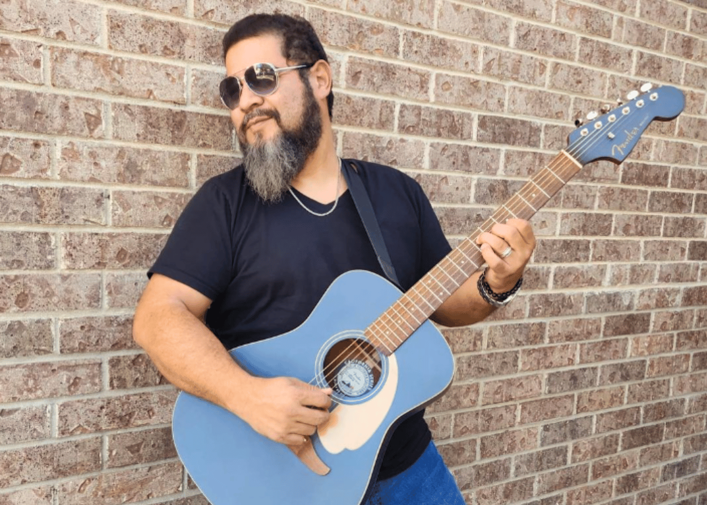 Musician Jaime Varela with guitar leaning on wall