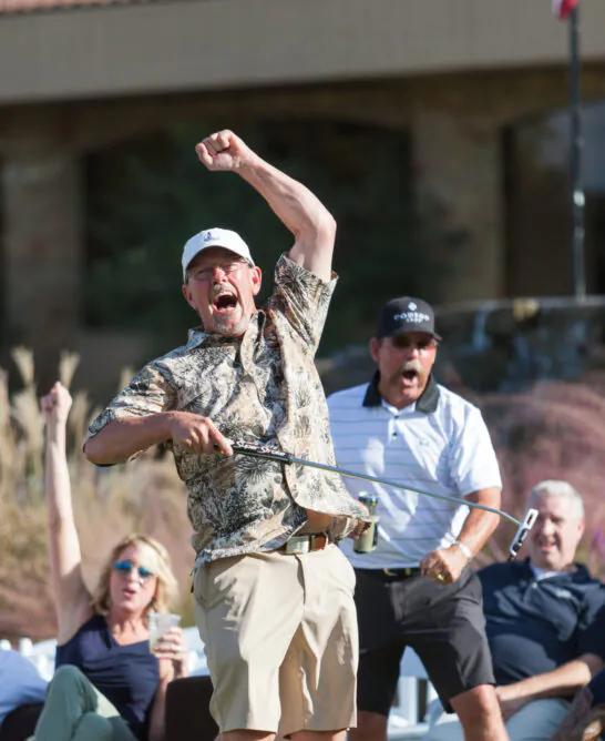 man swinging golf club with crowd watching