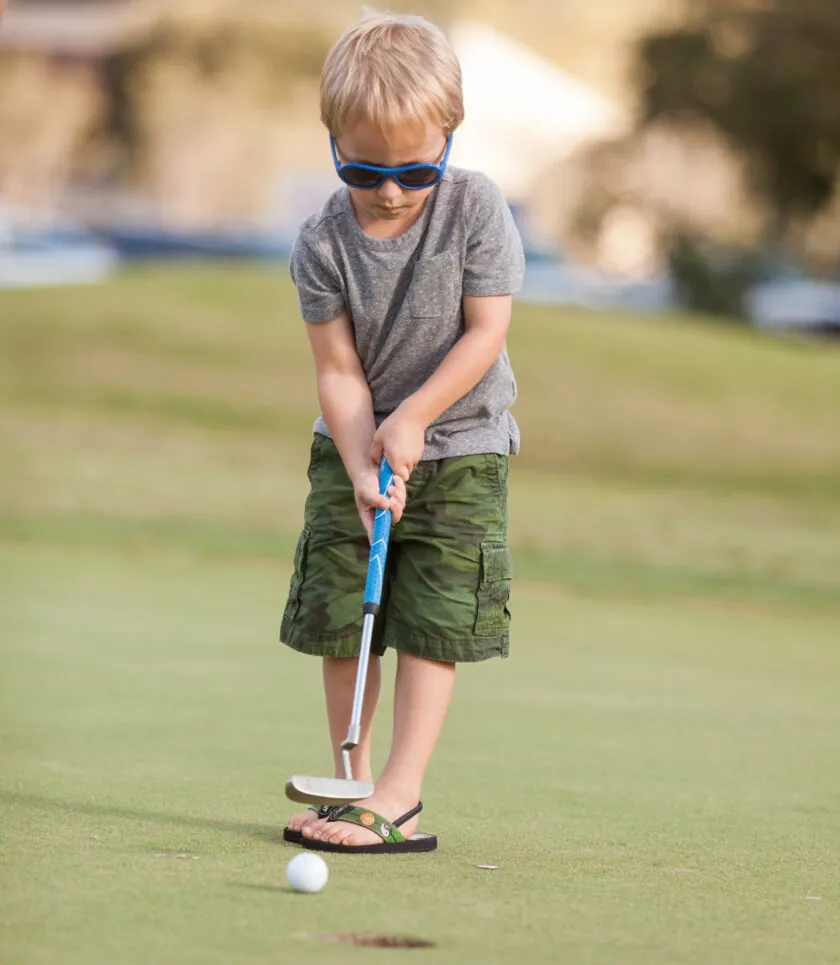 A child with sunnglases playing Golf