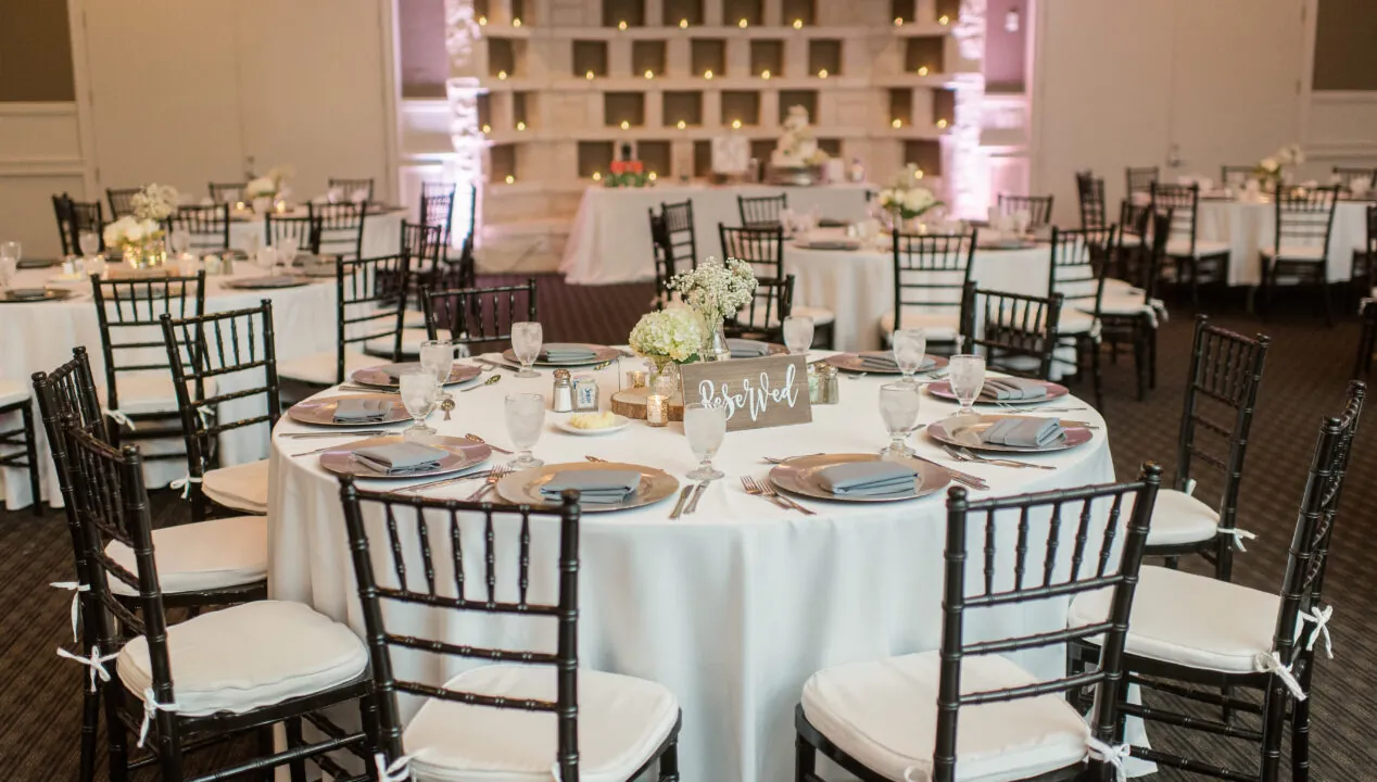 indoor wedding reception with round tables and black chairs