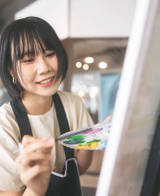 woman painting on canvas at easel