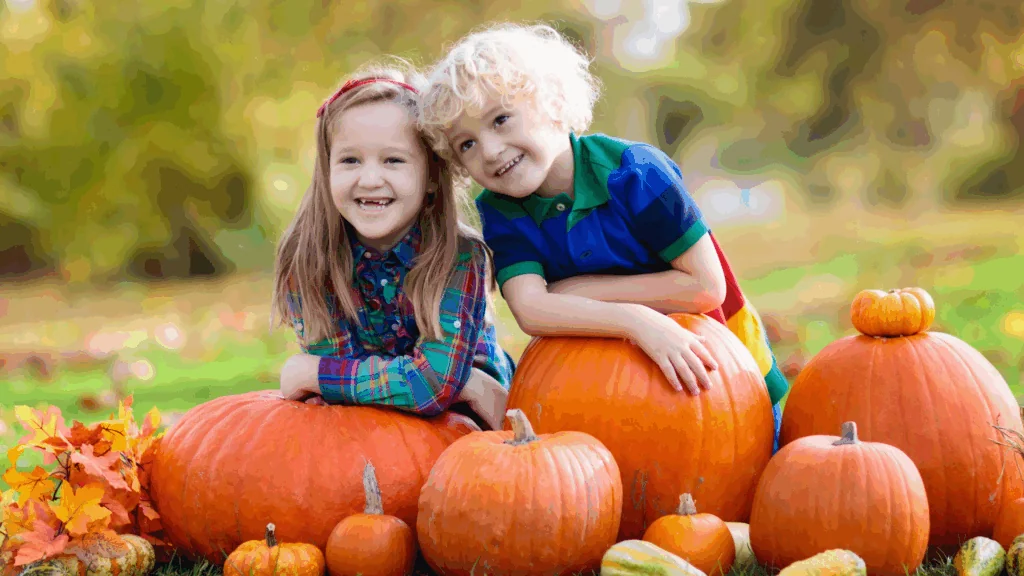 Children sitting on pumpkins
