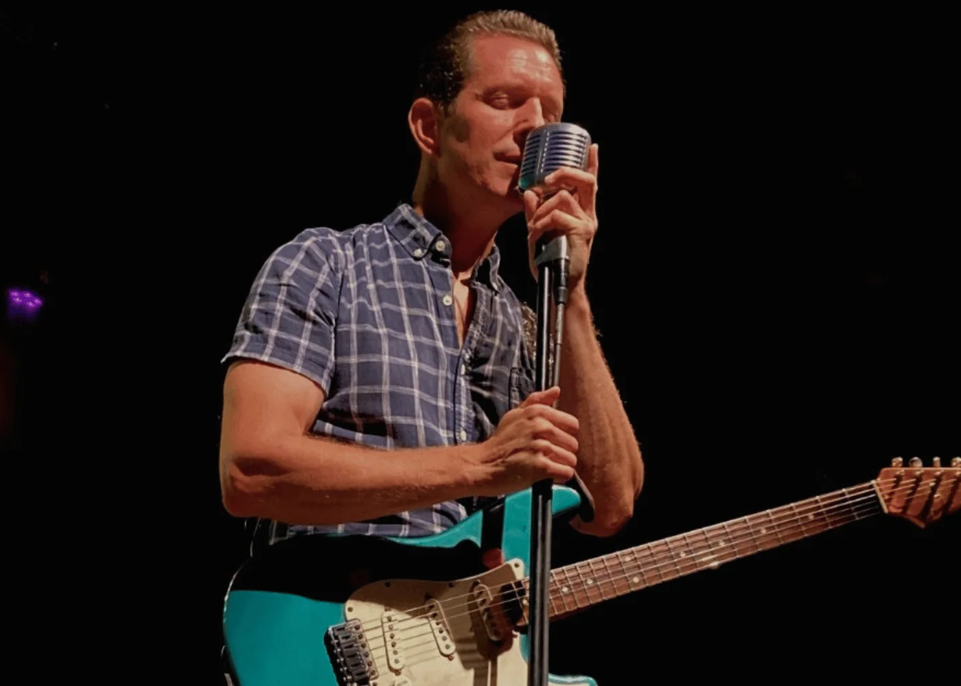 Men with guitar singing on stage