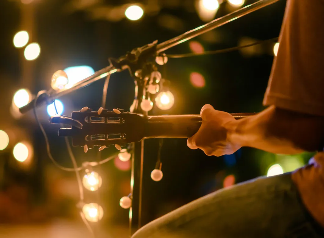 Guitar player under string lights